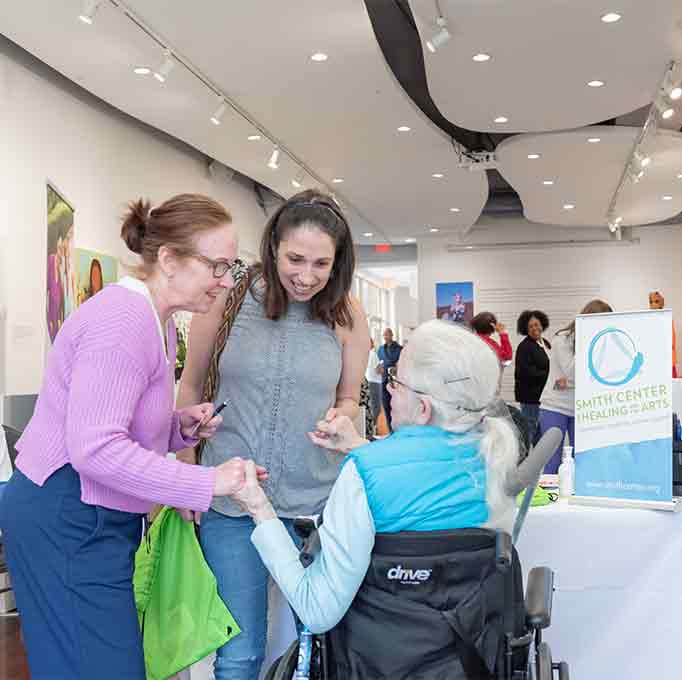 Smith Center staff talk to a patient and caregiver at an event